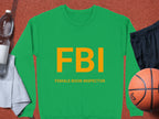 This unisex Garment Graphics green sweatshirt boasts bold yellow FBI lettering with Female Boob Inspector beneath. Its shown on a brown surface with a white bottle, gray towel, black shorts, and basketball. Ideal for those who appreciate humor and style!.