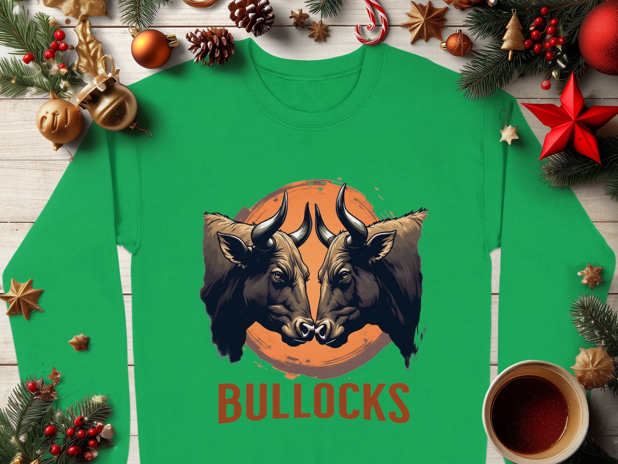 This green unisex long-sleeve shirt by Garment Graphics features two forward-facing bulls on an orange circular background, with BULLOCKS printed below amidst pine branches, ornaments, and a coffee cup on wood.