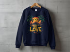 A navy Garment Graphics sweatshirt on a wooden hanger displays a sunset with palm trees and bird silhouette, highlighted by bold One Love text against a concrete background. Part of the One Love Sweatshirts line, it offers unisex sizing for versatile style.