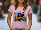 A person wears a Garment Graphics pink T-shirt with I Love Graffiti in vibrant text, featuring paint splatters, spray painter silhouettes, and a heart design—ideal for urban design lovers. The background is softly lit and blurred.