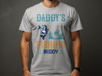 A person is wearing a Garment Graphics white t-shirt with a lively design featuring Daddys Fishing Buddy in blue and orange, showcasing a fish leaping near an angler—ideal for fishing enthusiasts.