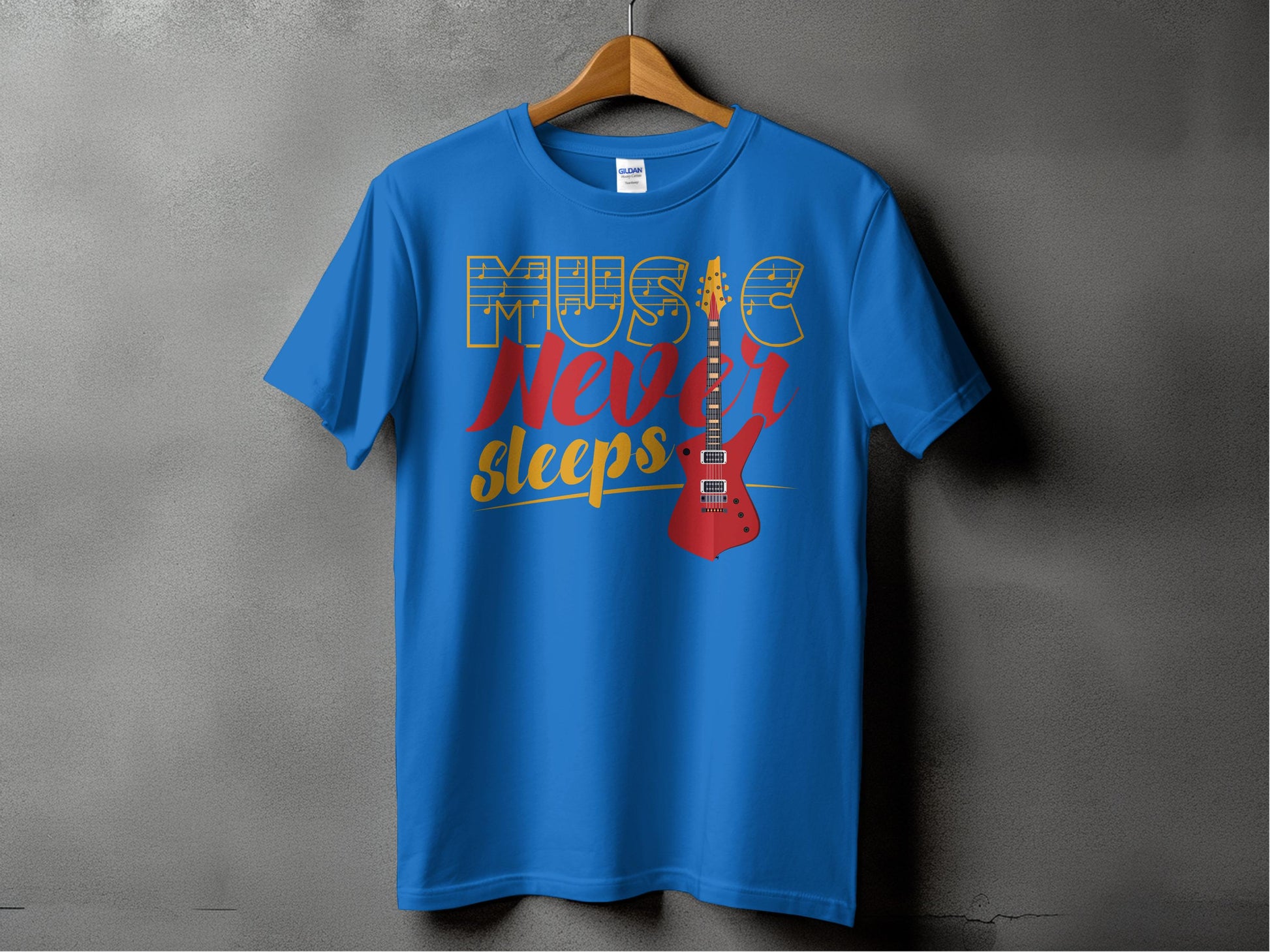 A blue 100% cotton T-shirt by Garment Graphics hangs on a wooden hanger against a gray wall. It showcases Music Never Sleeps in vibrant yellow, blue, and red with a striking red electric guitar graphic—ideal for Graphic T-Shirt enthusiasts.