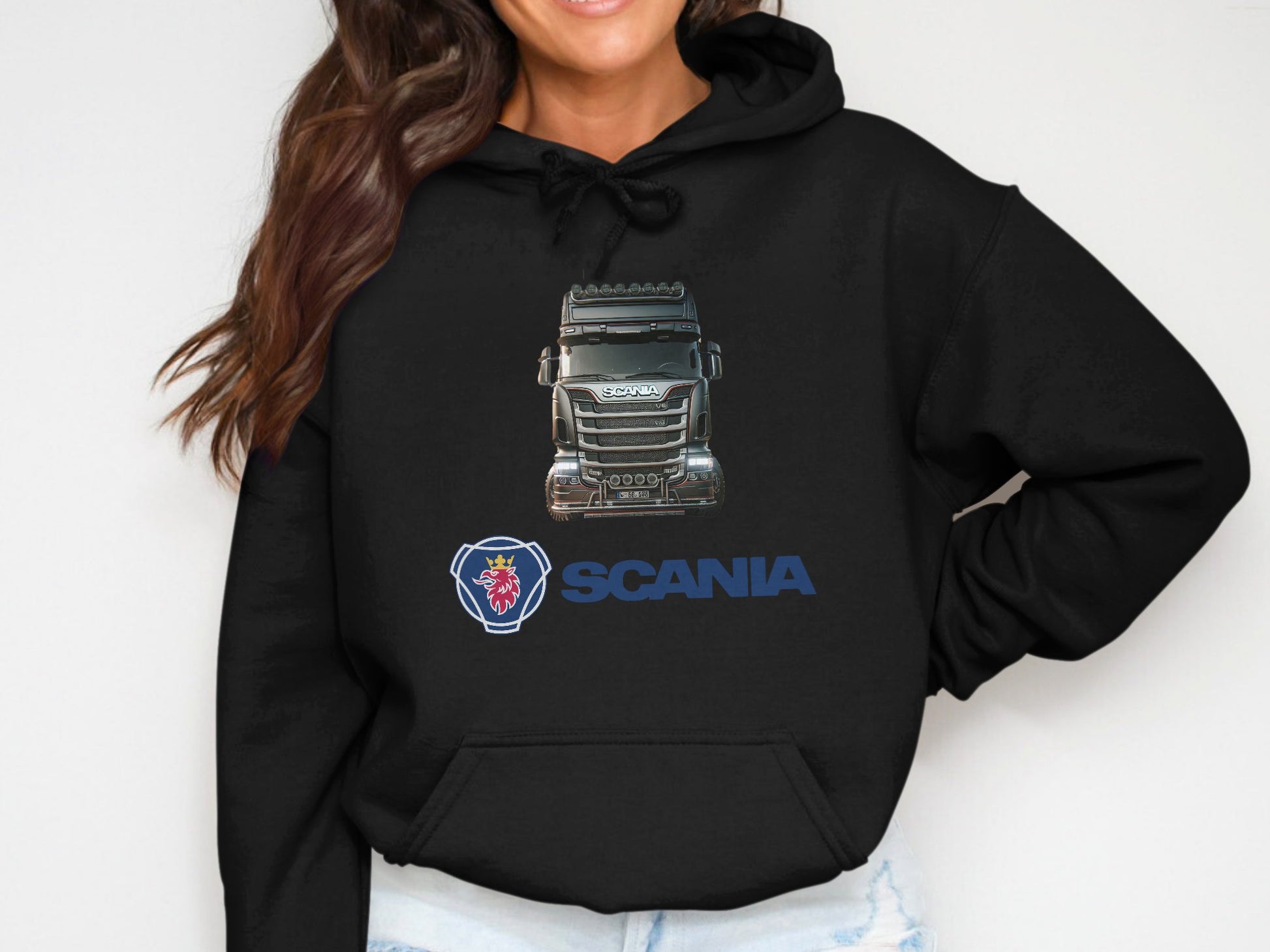 Someone with long brown hair showcases their love for graphic design by wearing a black hoodie from Garment Graphics. Featuring a Scania truck and the iconic red griffin head logo, its an ideal piece for truck enthusiasts.