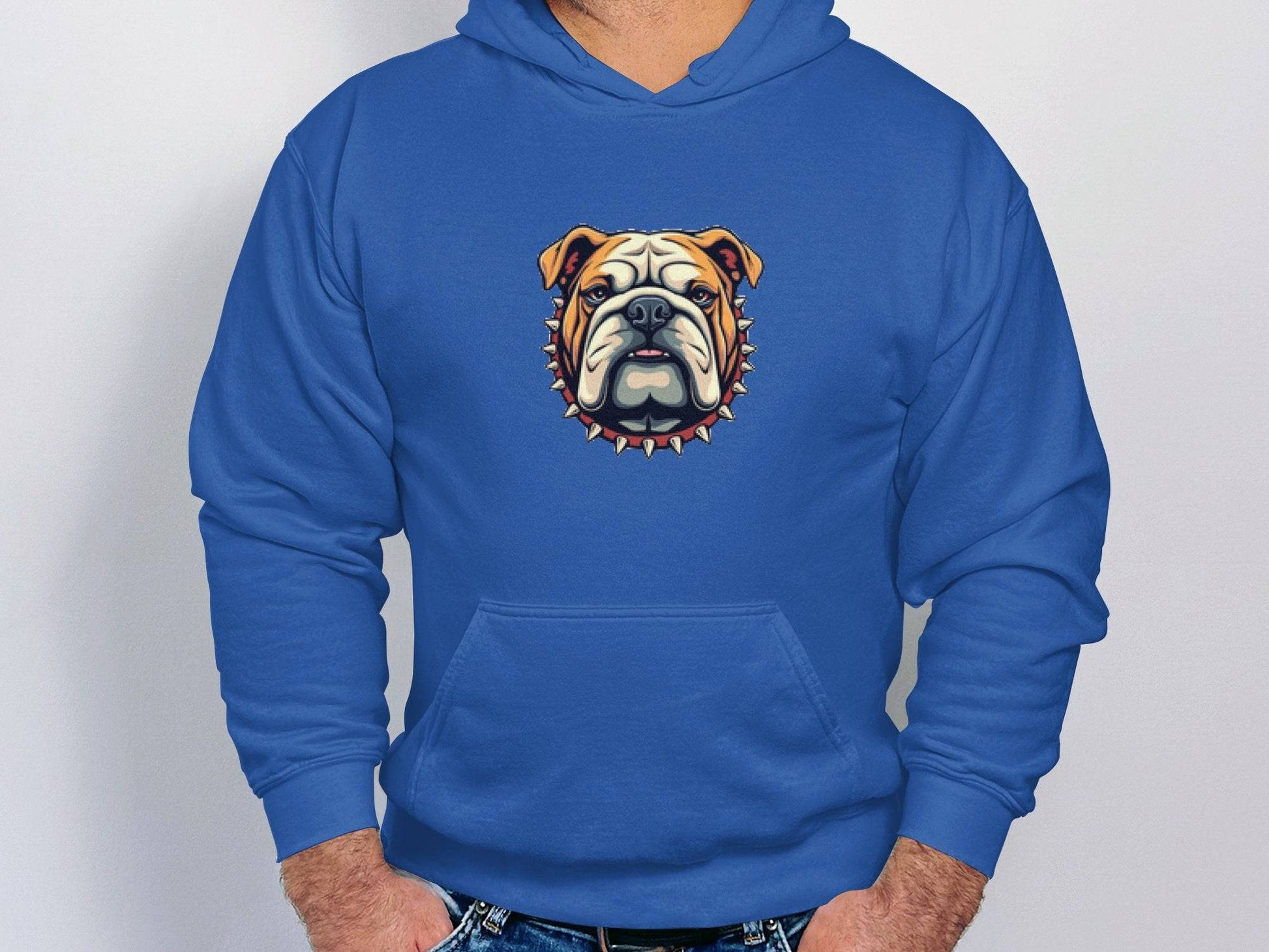 A person dons a Garment Graphics blue hoodie showcasing a striking bulldog design with a spiked collar on the front, hands casually tucked in pockets, standing against a plain white background.