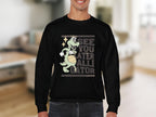 A person in a Garment Graphics black graphic sweatshirt featuring a cartoon alligator spinning a basketball with the text See you later, Alligator. This stylish, unisex piece is set against a blurred indoor backdrop with neutral tones.