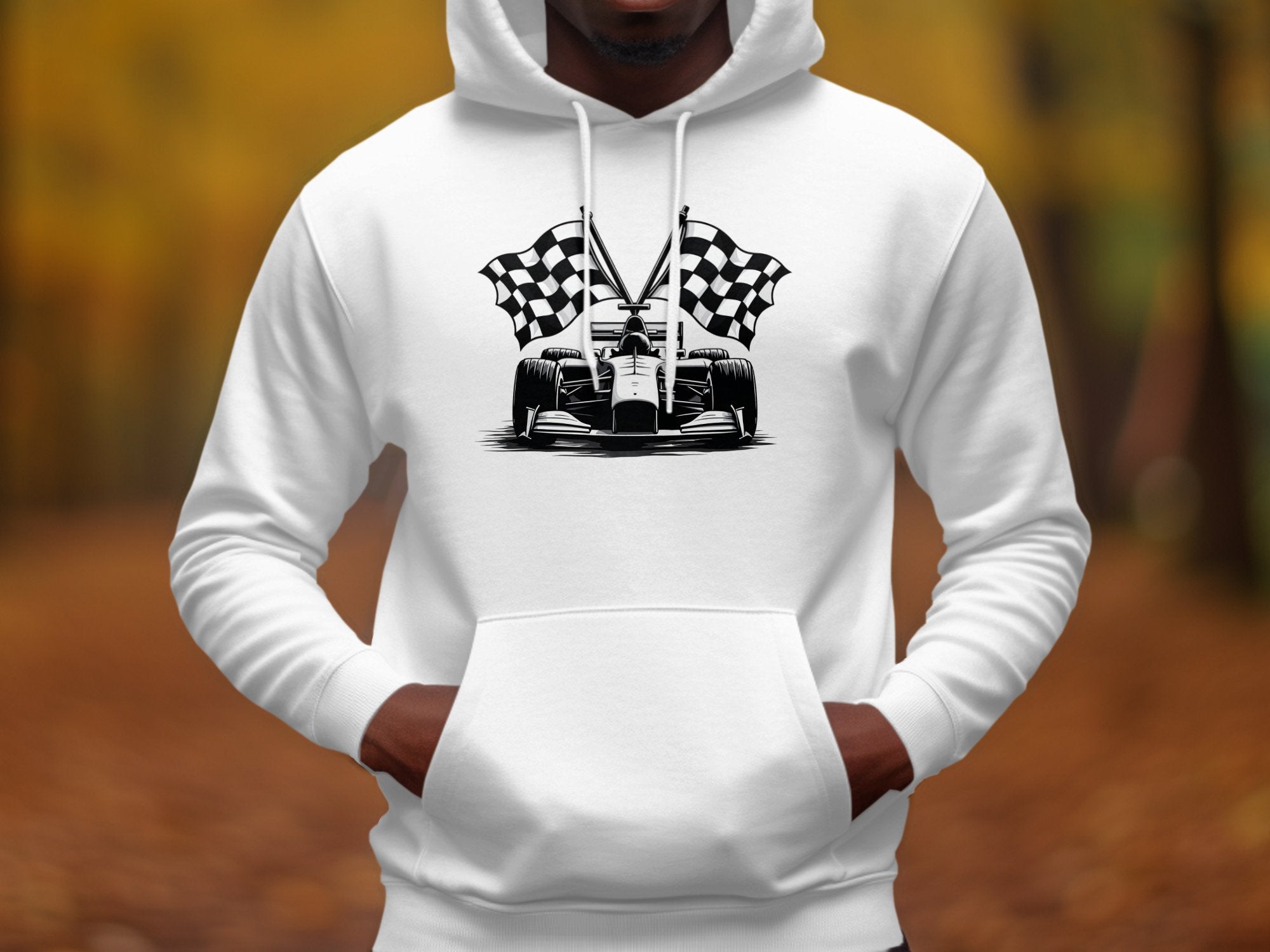 A person is wearing a white Garment Graphics hoodie featuring a bold racing theme with a race car and checkered flags graphic, set against an out-of-focus autumn background in rich brown and yellow tones.