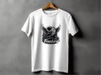 A white Garment Graphics 100% cotton T-shirt hangs against a gray wall, featuring a bold graphic of an eagle with outstretched wings and the text Freebird below.