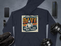 The Garment Graphics hoodie features Just Dave Doing Dave Things with an illustration of a man. Made from medium-heavy fabric, it lies on a gray surface with a smartphone, smartwatch, wireless speaker, sneakers, and dumbbells.