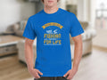 A person wears a blue T-shirt by Garment Graphics with Father and Son: Fishing Partners for Life in yellow and white. The design features a fishing rod and anchor, celebrating the father-son bond for those who treasure their special connection.