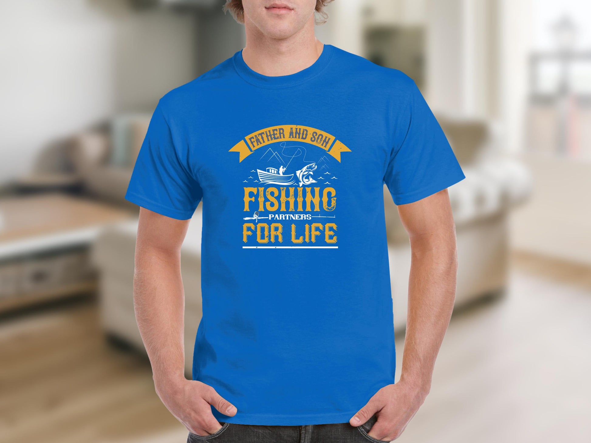 A person wears a blue T-shirt by Garment Graphics with Father and Son: Fishing Partners for Life in yellow and white. The design features a fishing rod and anchor, celebrating the father-son bond for those who treasure their special connection.