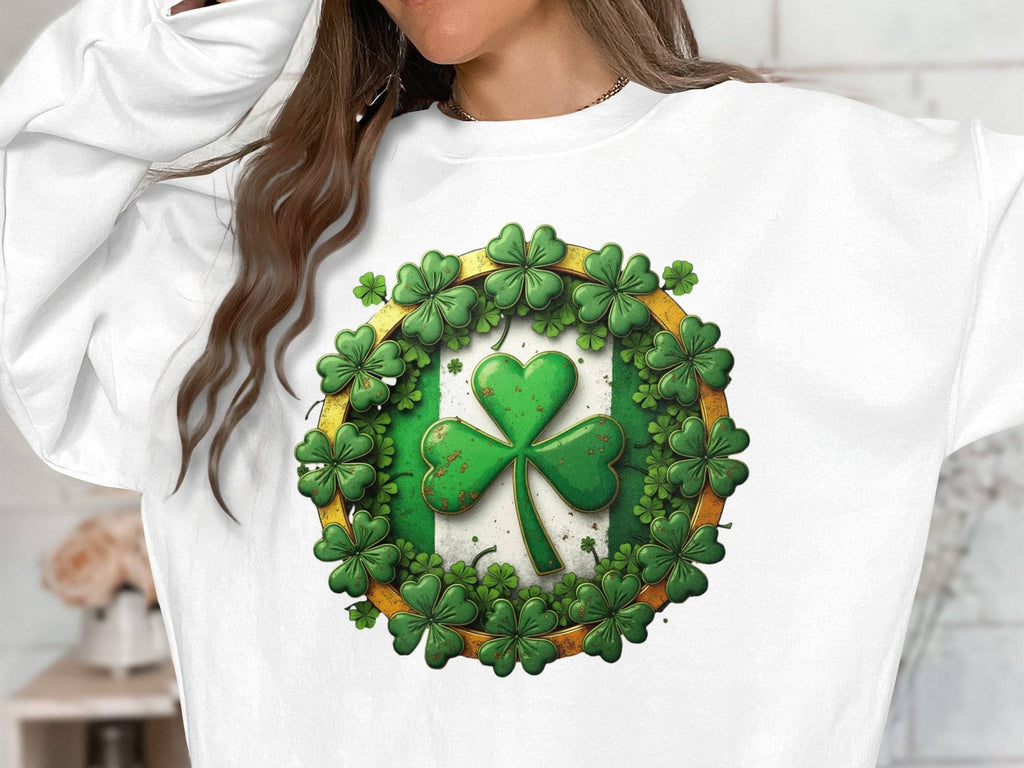A person wears a Garment Graphics white sweatshirt showcasing Irish spirit with a large green shamrock encircled by smaller ones, capturing the essence of Circle Design Sweatshirts. The textured design contrasts perfectly against the neutral backdrop, though their face remains unseen.