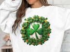 A person wears a Garment Graphics white sweatshirt showcasing Irish spirit with a large green shamrock encircled by smaller ones, capturing the essence of Circle Design Sweatshirts. The textured design contrasts perfectly against the neutral backdrop, though their face remains unseen.
