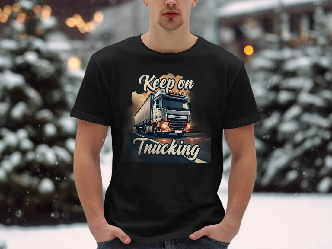 A truck enthusiast wears a Garment Graphics white t-shirt with a large truck graphic on a road, Keep on Trucking text, and a grassy field under a clear sky backdrop.