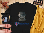 Laid on a wooden surface is a black crewneck sweatshirt featuring a Scania truck design by Garment Graphics. Perfect for truck lovers, its paired with items like a yellow blazer, pink loafers, sunglasses, makeup brushes, an open eyeshadow palette, and a lipstick-topped compact mirror.