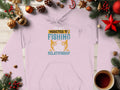 The Garment Graphics fishing hoodie, featuring the text Im not addicted to fishing, we are just in a very committed relationship, is surrounded by Christmas decorations—pine branches, ornaments, pinecones—with a steaming mug of coffee on the classic wooden surface.