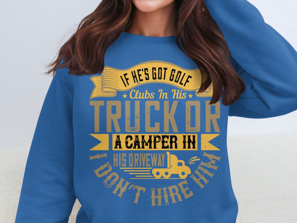 A person is wearing a humorous Garment Graphics sweatshirt. Its blue with yellow text and graphics, reading If hes got golf clubs in his truck or a camper in his driveway, I dont hire him, accompanied by a small camper illustration.