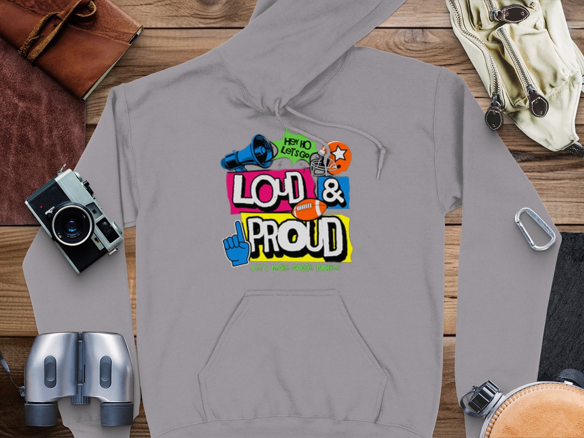 Garment Graphics’ gray hoodie features Loud & Proud in colorful text at its center, with a microphone, star, thumbs-up, and megaphone. It also declares Hey Ho Lets Go and Hit The Road Tour, ideal for adventurous spirits eager to make noise while traveling.