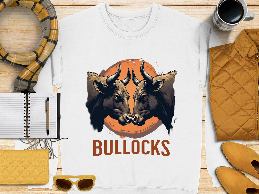 The striking white sweatshirt by Garment Graphics features a bullocks graphic with two bulls against a sunset and BULLOCKS below. Pair it with a yellow quilted jacket, notebook, pen, coffee cup, scarf, glasses, and clutch for a perfect laid-back style.