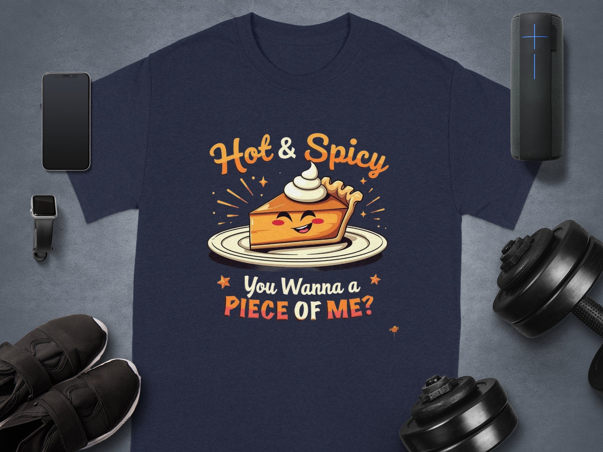 Garment Graphics offers a navy T-shirt featuring a hot and spicy pie design topped with Hot & Spicy and You Wanna a Piece of Me? below. Perfect for family sizing, it pairs well with accessories like phones, smartwatches, sneakers, speakers, and dumbbells.