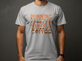 A person wears a gray Garment Graphics T-shirt featuring Running on Grace & Coffee in vibrant orange and brown. The design includes decorative swirls and coffee cup motifs on a plain dark background.