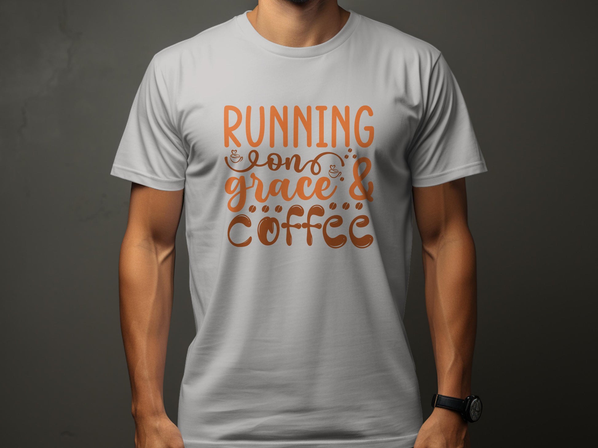A person wears a gray Garment Graphics T-shirt featuring Running on Grace & Coffee in vibrant orange and brown. The design includes decorative swirls and coffee cup motifs on a plain dark background.