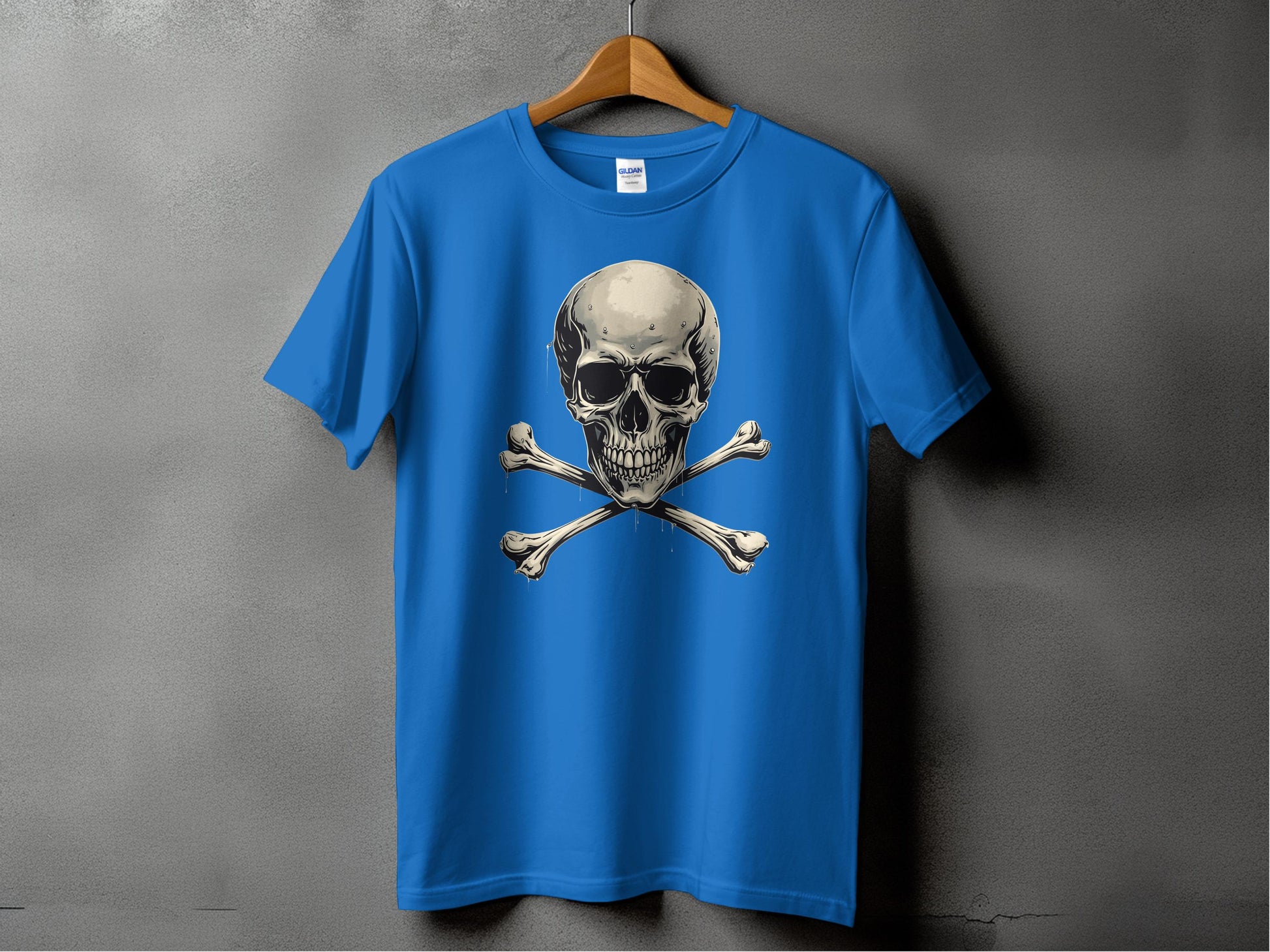 A bold blue graphic t-shirt by Garment Graphics, featuring a skull and crossbones design, is displayed on a wooden hanger against a gray backdrop.
