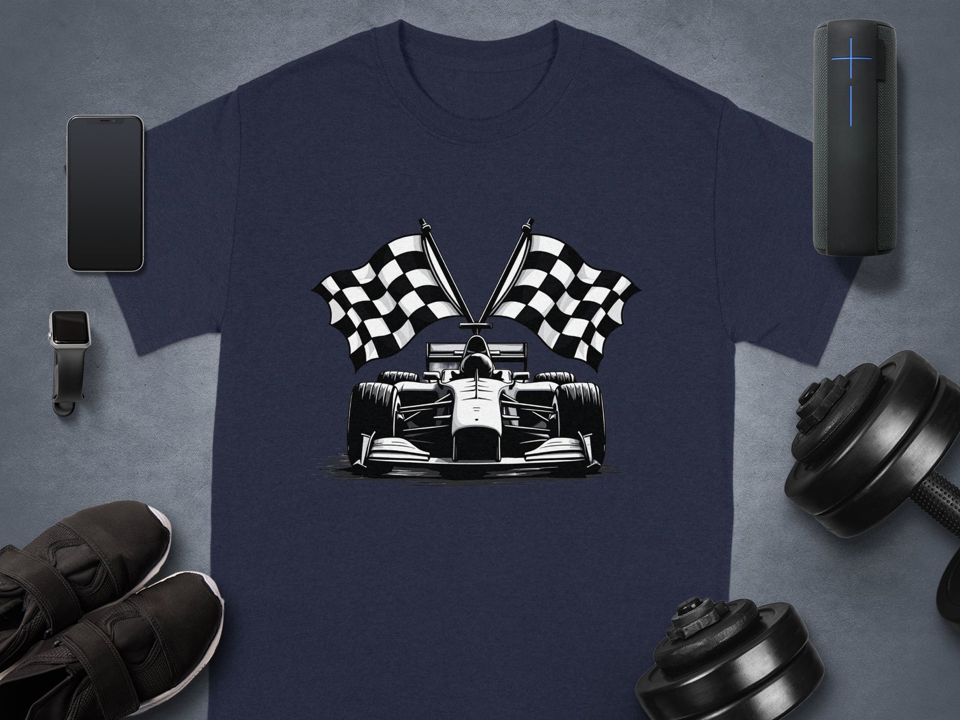 A Garment Graphics navy blue T-shirt displays a Formula One car and crossed checkered flags. The shirt is styled with a smartphone, smartwatch, speaker, sneakers, and dumbbells on a sleek gray background.