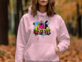 A person wears Garment Graphics pink hoodie with a I Love Graffiti design in colorful urban street art lettering, perfect for any casual wardrobe. The backdrop is an outdoor setting with blurred autumn foliage.