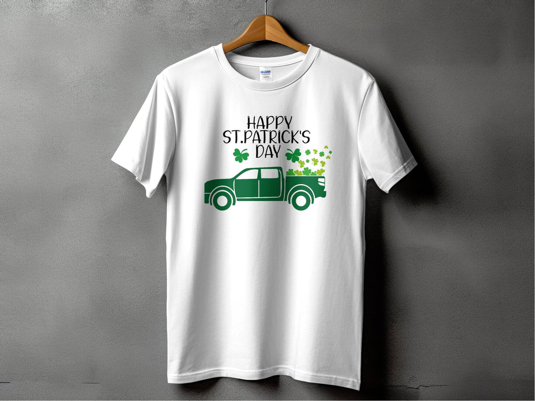 A man in a Garment Graphics green T-shirt with Happy St. Patricks Day proudly showcases Irish pride alongside a truck adorned with shamrocks, set against a sandy backdrop with grass, creating a festive atmosphere.