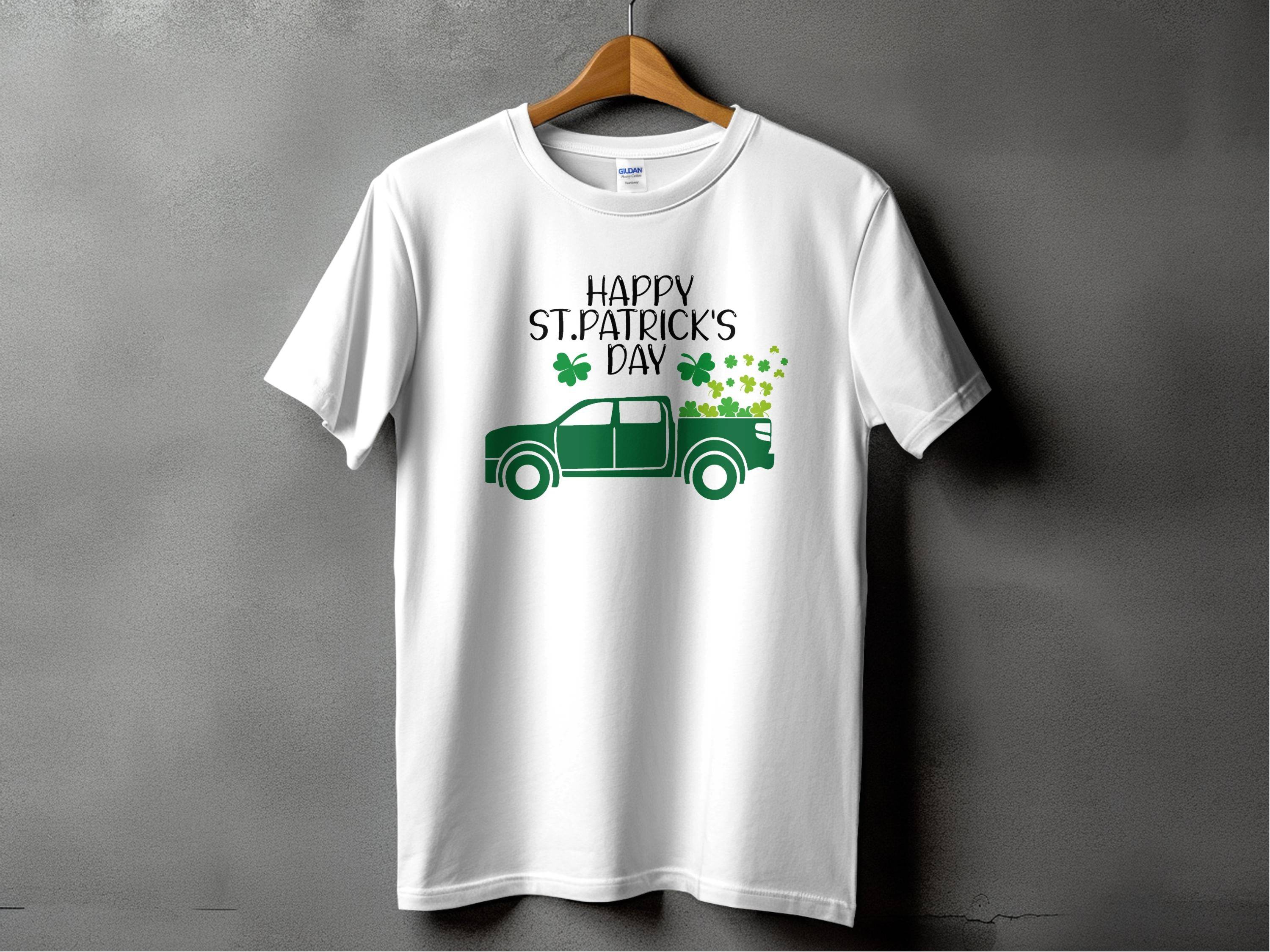 A white T-shirt by Garment Graphics displays a green pickup truck with shamrocks and the phrase Happy St. Patricks Day above it, set against a gray background, celebrating Irish pride.