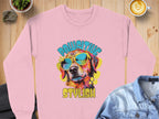 Garment Graphics presents a pink sweatshirt featuring a vibrant dog graphic and the phrase Pawsitive Stylish, perfect for dog enthusiasts. The design includes a cool canine in sunglasses, artistically paired with a denim jacket and coffee on a wooden table.