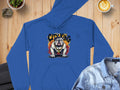 The blue Classic Fit Graphic Bulldog Design Hoodie by Garment Graphics showcases a bulldog in a spiked collar on flames with CITY KING text. Styled on wood alongside a denim jacket, latte, and potted plant, its an ideal addition to your casual wardrobe.