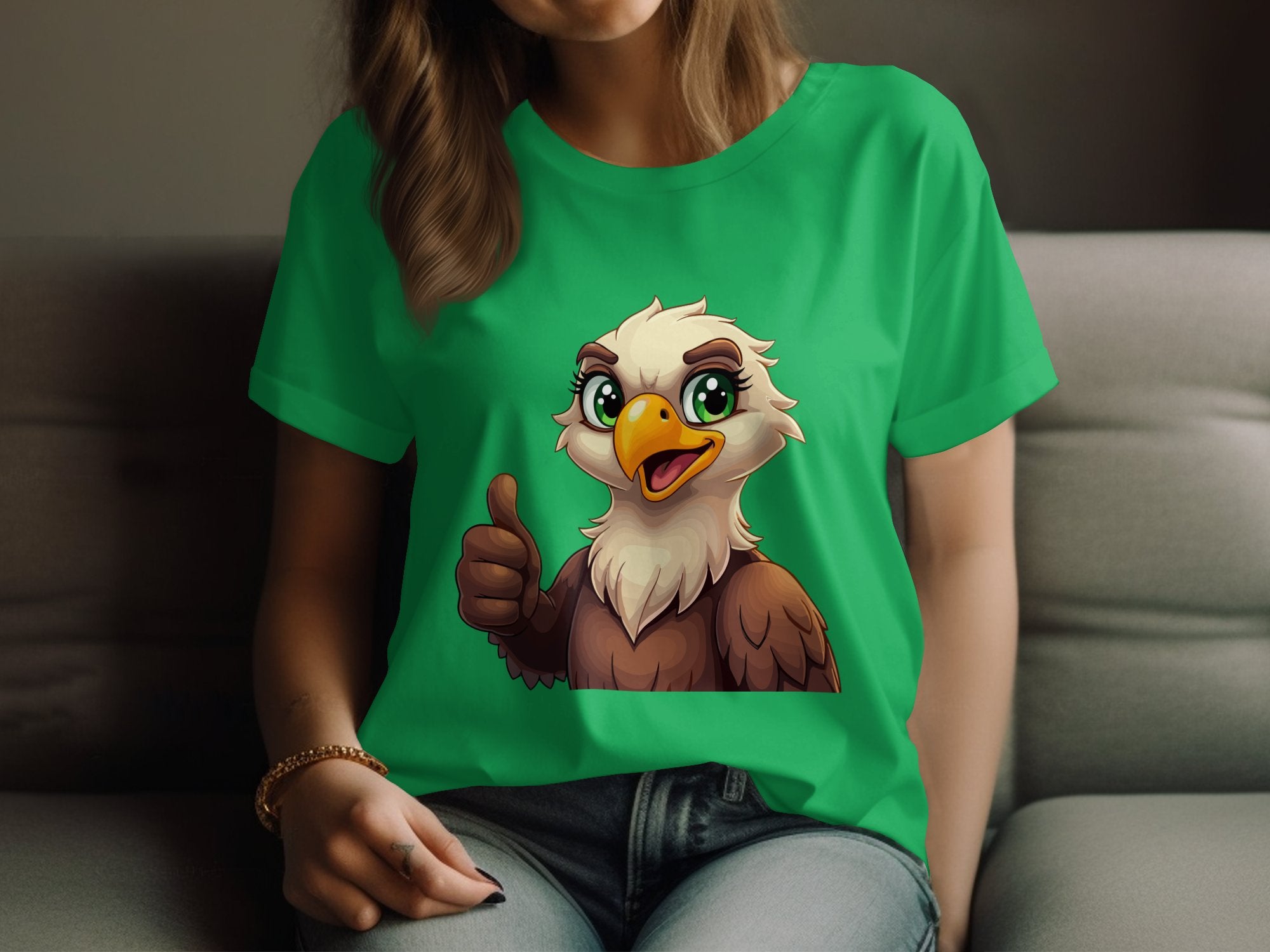 A person is lounging on a couch in a bright green Garment Graphics T-shirt featuring a thumbs-up cartoon eagle. The look is complete with blue jeans and a bracelet, ideal for animal lovers.