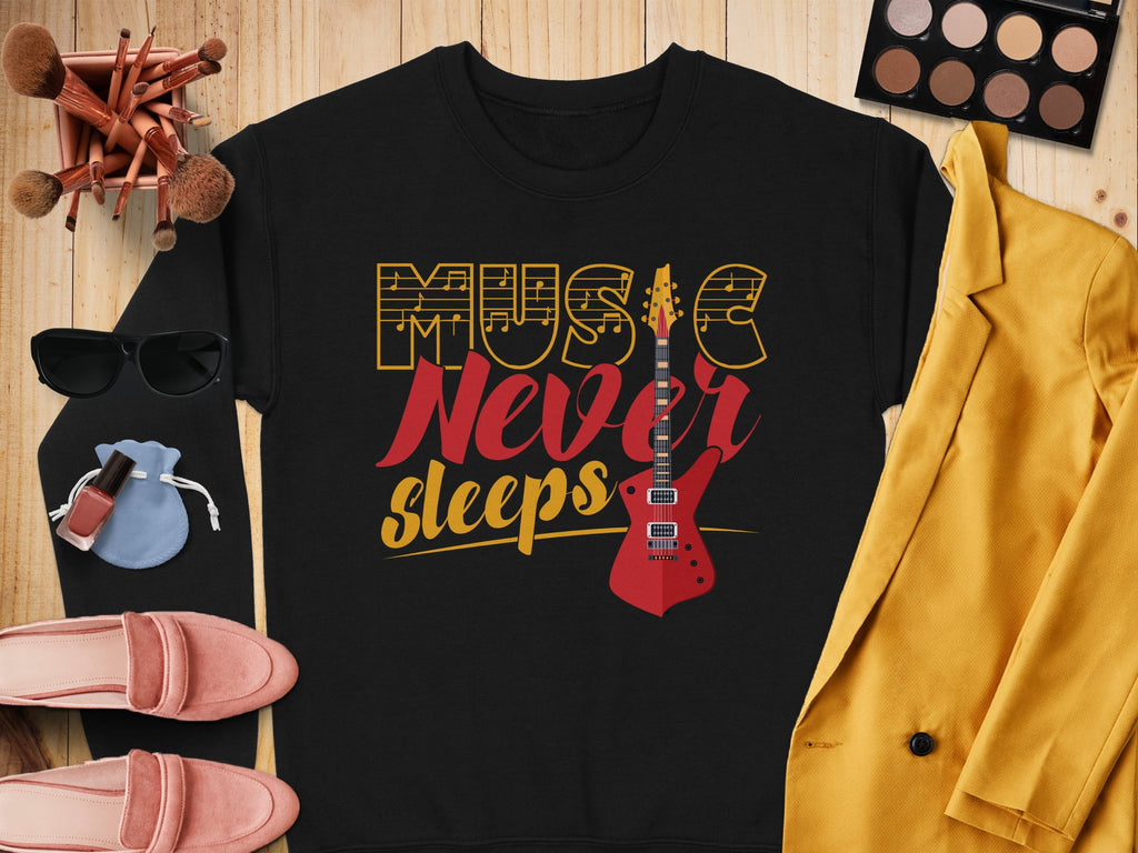 A stylish Garment Graphics sweatshirt with the Music Never Sleeps Guitar design is displayed on a wooden surface. Surrounding it are makeup brushes, an eyeshadow palette, sunglasses, a yellow jacket, a small bag, nail polish, lipsticks, and pink shoes—ideal for music lovers with fashion flair.