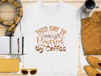 Garment Graphics presents a playful white graphic sweatshirt with This day is powered by coffee in brown lettering, surrounded by a notebook and pen, yellow scarf, steaming cup of coffee, quilted jacket, sunglasses, and a chic quilted purse design.