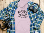 A light pink Garment Graphics hoodie featuring the humor-filled quote, I had my patience tested, Im negative, is styled on a wooden surface with a blue plaid shirt, headphones, and a camera—ideal for highlighting its unique design and flair.