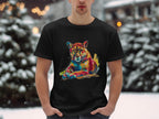 A person in a Garment Graphics black graphic print T-shirt, showcasing a colorful roaring cougar, stands outdoors in the snow with pine trees and blurred lights creating a serene backdrop that highlights the vibrant artwork of the majestic animal.