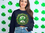 A woman wearing a navy blue sweatshirt by Garment Graphics, featuring a lucky four-leaf clover design, stands before a wall of green shamrocks. Her long brown hair cascades as she smiles, embodying the Irish spirit and pairing the look perfectly with denim jeans.