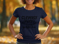 In a park with autumn leaves, someone stands confidently wearing Garment Graphics semi-fitted navy blue T-shirt. The shirt humorously displays Cleverly Disguised as a Responsible Adult in bold black text, featuring playful arrow graphics.