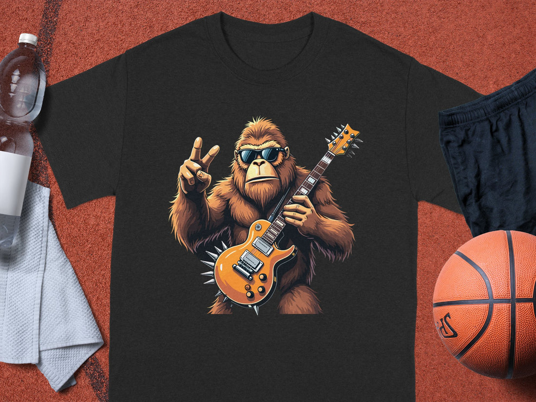 A Garment Graphics black t-shirt with a gorilla in sunglasses holding an electric guitar and flashing a peace sign. Ideal for music fans, it pairs well with a water bottle, towel, black shorts, and a basketball.