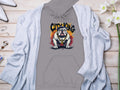 A gray Garment Graphics sweatshirt with an urban edge features a bulldog design with a gold chain and City King text. Its displayed on wood, paired with a light gray cardigan, jewelry, and white flowers for city chic flair.