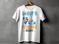 The Daddys Fishing Buddy Graphic Print T-Shirt by Garment Graphics, displayed on a wooden hanger, showcases vibrant blue and orange text. A charming fishing scene with a fish and person in a boat with a rod is set against the soft gray backdrop.