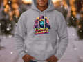 A person wears a Garment Graphics gray hoodie featuring colorful gorillas, with one in sunglasses and a hat. The Gorilla Gangster text adds flair to this streetwear piece, while blurred snowflakes in the background enhance its edgy vibe.