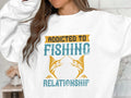 A model in a unisex white sweatshirt by Garment Graphics features a design with two fish and the phrase Addicted to Fishing Relationship, face not visible, against a blurred backdrop.