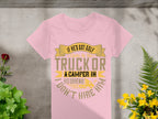 A Garment Graphics pink T-shirt, displaying a funny golf graphic and the quote If hes got golf clubs in his truck or a camper in his driveway, dont hire him, is styled on concrete with greenery and yellow flowers. Perfect for women who love quirky designs.