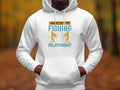 Wearing a Garment Graphics classic fit white hoodie, displaying Addicted to Fishing with a stylized fish and Relationship below. They stand before an autumn-hued natural backdrop, ideal for highlighting fishing hoodies.