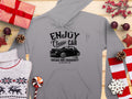 A gray hoodie by Garment Graphics features Enjoy Classic Car, Vintage Ride Community, Aircooled on a wooden surface with wrapped gifts, snowflake sweater, pine cones, candy, lollipop, and red stars—perfect for vintage car enthusiasts and community spirit.