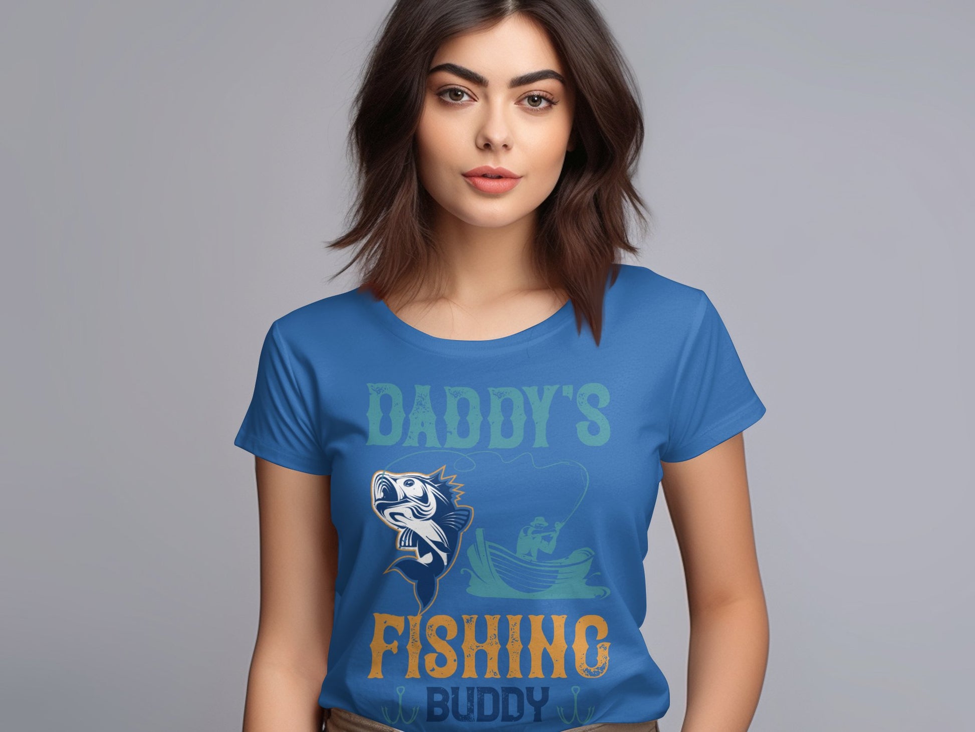 A woman with brown hair wears a Garment Graphics blue fishing shirt featuring Daddys Fishing Buddy and a fish and fisherman graphic. The plain gray background highlights her proudly displayed shirt.