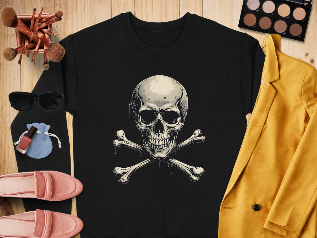A Garment Graphics black shirt with a skull and crossbones design rests on wood, radiating edgy style. It is surrounded by makeup brushes, sunglasses, a pink purse, nail polish, pink shoes, an eyeshadow palette, and a vibrant yellow jacket.