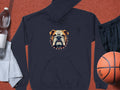 A dark blue hoodie with a bulldog design and spiked collar from Garment Graphics is displayed next to a white towel, clear plastic water bottle, black athletic shorts, and an orange basketball.